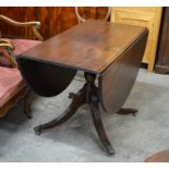 Mahogany drop leaf dining table on turned column and quadraform supports with brass caps and castors