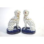 A pair of Staffordshire dalmatian dogs seated on oval bases, 13.5 cm high (2)One base has a chips