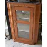 A stained pine hanging corner cupboard with single glazed door enclosing two shelves