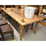 A large pine rectangular kitchen dining table raised on turned supports