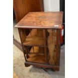 Early 20th century oak revolving bookcase, quadraform base with castors, the top with plaque