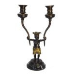 A parcel gilt twin branch candelabra supported by the figure of a young native boy, 36 cm high