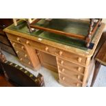 A stripped pine knee hole desk with gilt tooled green leather top over over a central panelled