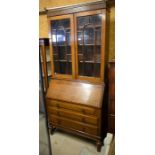 Oak bureau bookcase with a pair of glazed doors and fall front panel with fitted interior over three