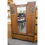 Art Nouveau oak wardrobe with floral embossed copper panels and central mirrored door over a