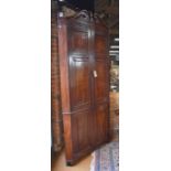 A George III mahogany full height two part corner cupboard, the moulded broken swan-neck cornice