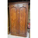 A Victorian mahogany tall wardrobe with full length panelled doors enclosing hanging space over a