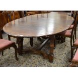 A good quality oak extending dining table, the rounded top with central leaf raised on turned