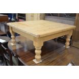 A stained pine square top coffee table on turned supports