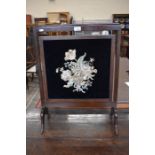 A mahogany fire screen with floral silk embroidery on velvet panel