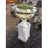 A pair of weathered stonecrete garden urns raised on square plinths, later painted (2)