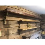 A pair of reclaimed stripped pine shelves with cast brass wall brackets to/with a heavy oak wall