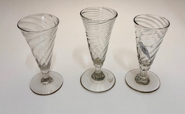 Three Georgian short ale glasses each with a wrythen trumpet bowl, knop and stem, conical foot and