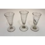 Three Georgian short ale glasses each with a wrythen trumpet bowl, knop and stem, conical foot and