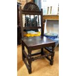 A 17th century carved oak hall chair, the arched moulded crest over four vertical barley-twist turns