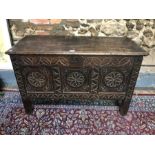 A 17th /18th century oak coffer, the wide two plank top over a lunette carved frieze and triple