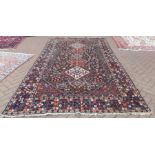 A Persian Qashqai kelleigh carpet, linked diamond medallions on dark brown field decorated with