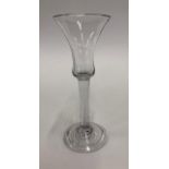 An 18th century wine glass with waisted bell bowl, plain stem, conical fold-over foot and rough