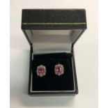 A pair of cluster earrings, the oval pink stones surrounded by small diamonds, white metal set,