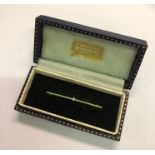 A narrow Art Deco bar brooch with pale green enamel and central seed pearl, on 9ct yellow gold knife
