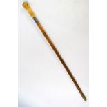 A 19th century malacca swagger stick, the ivory handle carved as a native figure supporting a basket