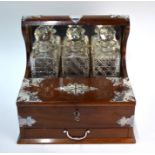 A mahogany tantalus with electroplated mounts, fitted with three square cut glass decanters, cigar