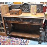 A Gothic revival carved oak console table with raised back over two frieze drawers and turned