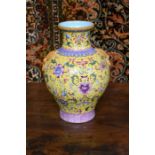 A Chinese famille rose vase decorated with floral designs on the yellow ground, 28 cm high; the base