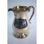 A heavy quality silver pear-shaped jug in the Georgian manner, with scroll handle and raised moulded
