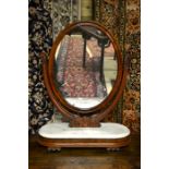 A Victorian mahogany framed oval mirror raised on a marble topped platform base, 83 cm h