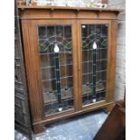 An Art Nouveau period leaded and coloured glass panelled oak bookcase, the interior with