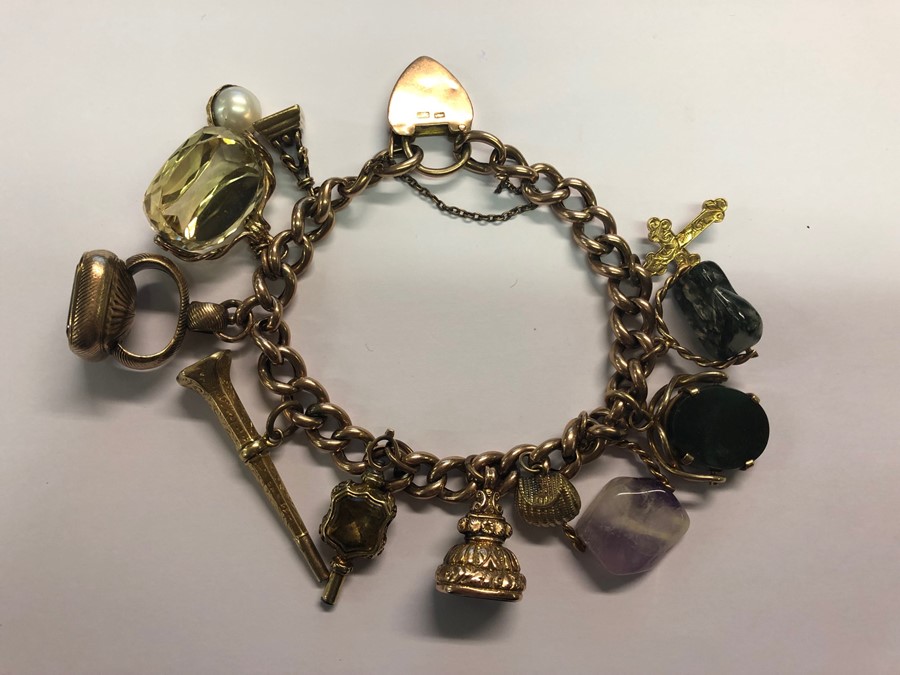 A 9ct rose gold curb bracelet with padlock and safety chain, with twelve various charms attached