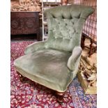 A Victorian green button backed nursing chair raised on turned front legs to brass castors, the back