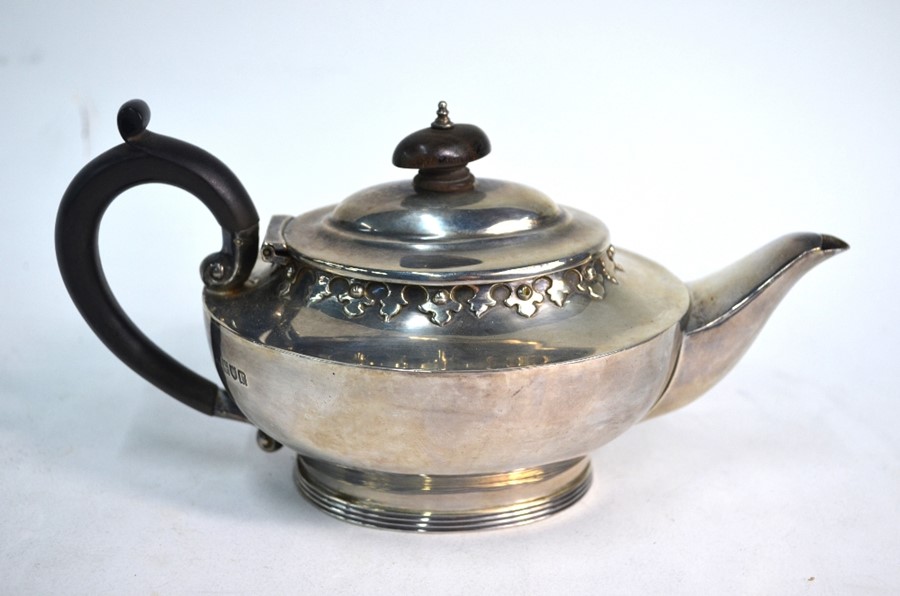 An oval silver bachelor teapot with Gothic-style embossed rim and reeded foot, Charles Edwards,