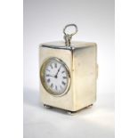 A late Victorian silver boudoir clock with circular enamel dial, hinged loop top handle and bun