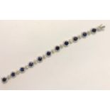 A diamond and sapphire set bracelet formed of eleven oval sapphires with diamond surround, and