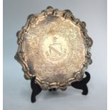 A George II silver salver with shell and scroll moulded rim, on three scroll feet, engraved with