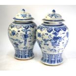 A pair of Chinese blue and white vases, each one with a domed cover and knop finial, decorated