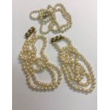 A pair of uniform rows of cultured pearls knotted throughout onto yellow metal fancy clasp set