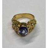 An 18ct yellow gold ring, the large central oval blue stone, possibly pale tanzanite, with wide
