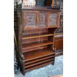 A good quality Art Nouveau period red walnut library cabinet, the fret-cut three-quarter gallery top