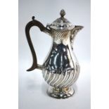 An Edwardian silver pear-shaped hot water jug with writhen reeding and domed foot William Hutton &