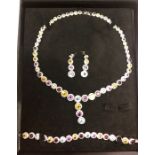 A white metal and coloured stone-set suite comprising necklace, bracelet and drop earrings,