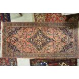 An old Persian Mashad rug, the centre medallion design on salmon ground, 197 x 95 cm [89]