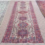 A Persian Heriz runner, geometric medallions and stylised motifs on cream ground with boteh