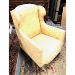 A 19th century wing armchair upholstered in ochre floral linen, raised on square form legs to