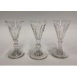 Three Georgian wine glasses with fluted trumpet bowls, two with baluster stems and one with a fluted