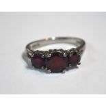 A three-stone garnet ring, set white metal stamped 925 (shank misshapen)