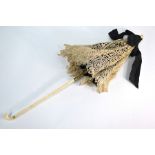 A 19th century lace and silk parasol on foliate-carved folding ivory handle with gilt mounts, by