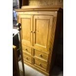 A waxed pine cupboard with panelled doors over four drawers raised on a plinth base 109 cm wide x 48